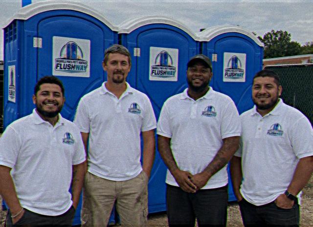 Service crew standing in front of a row of portable toilet units